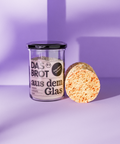 Glas mit Brotbackmischung "Das Brot aus dem Glas" und angeschnittenem Brotlaib. Bio, nachhaltig und vegan für frisches Brot zuhause.