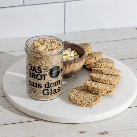 Bio Haferbrot im Glas mit Scheiben aufgeschnitten – praktisches, frisches Brot zum Selberbacken, serviert mit cremigem Dip auf modernem Marmorteller.